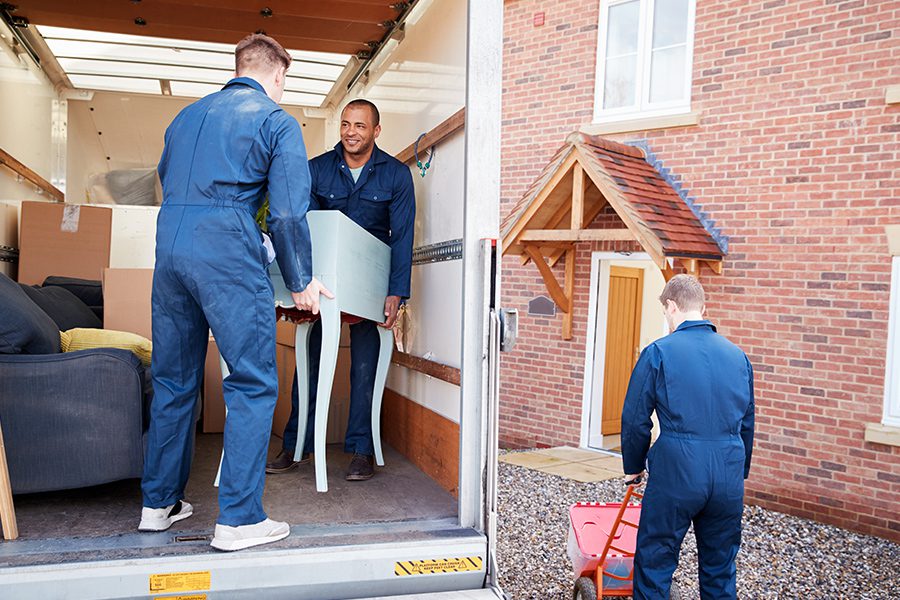 Moving and Storage Insurance - Moving and Storage Workers Unloading Furniture And Boxes From Truck Into New Home On Moving Day