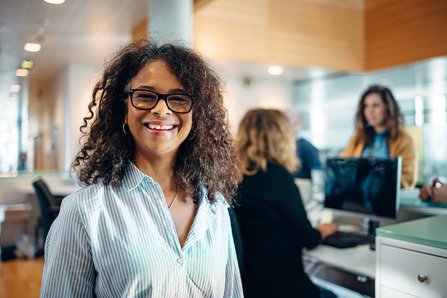 Specialized Business Insurance - Friendly Municipal Office Administrator Portrait with Reception Area Blurred in the Background