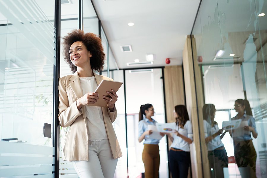 Specialized Programs - Successful Business Woman Smiling and Looking Out Her Office Window