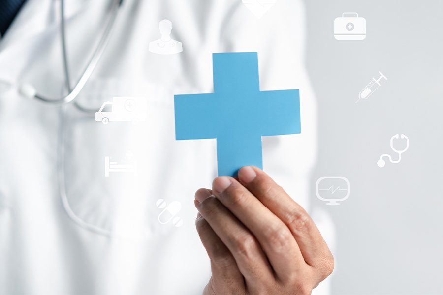 Pharmacy Insurance Network - Close-up of a Doctor Holding a Blue Medical Cross with Other Health Icons Sourrounding It